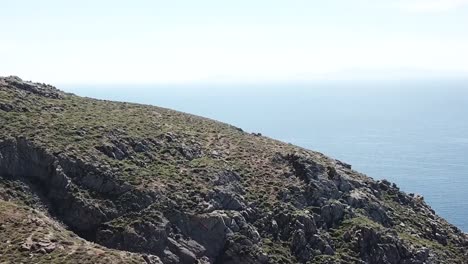 aerial drone mykonos greece pan up cliffside beach