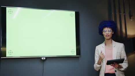 biracial casual businesswoman making presentation with tablet in office, copy space, slow motion