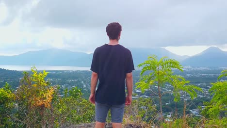 man enjoying the view of a city still asleep under the cover of clouds, like the mountains in the distance, slow motion