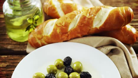 Olive-oil,-bread-loaf-and-pickled-olives-on-table