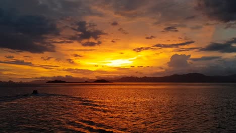 divers on a dingy moving off in a fiery sunset in pulau siaba kecil dive site in komdo indonesia for night dive