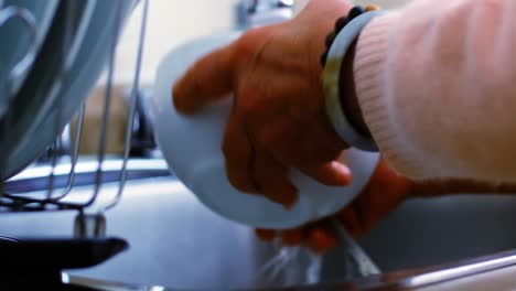 senior woman washing utensils at home