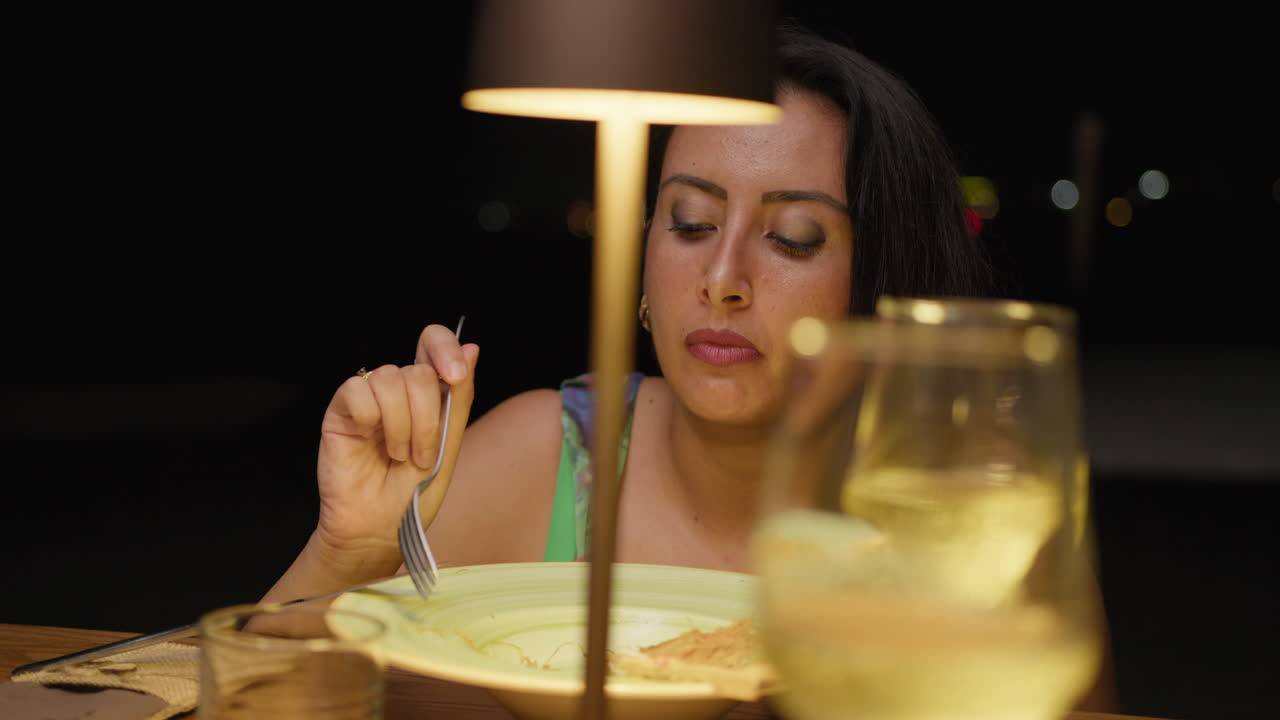 Light Of A Lamp Over The Woman Having Dinner Outdoor At The Restaurant