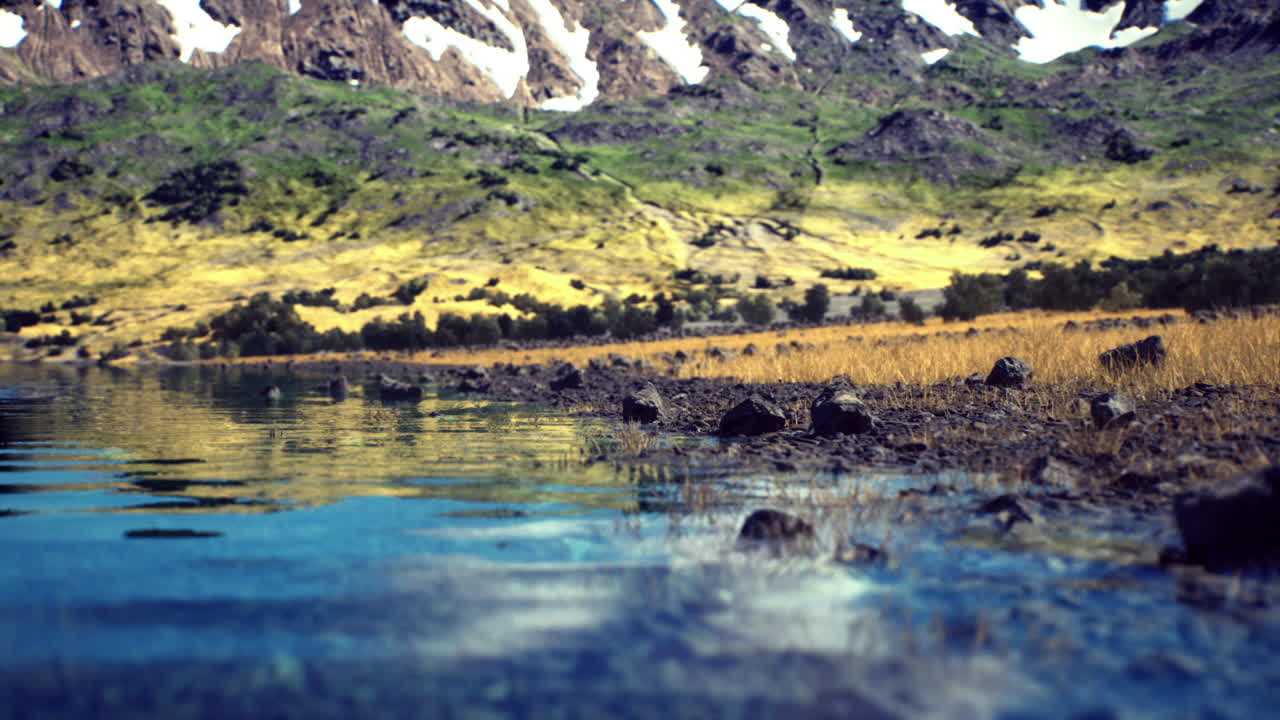 Arroyo resplandeciente se encuentra con un lago de montaña, picos nevados rodean un cuerpo de agua vibrante