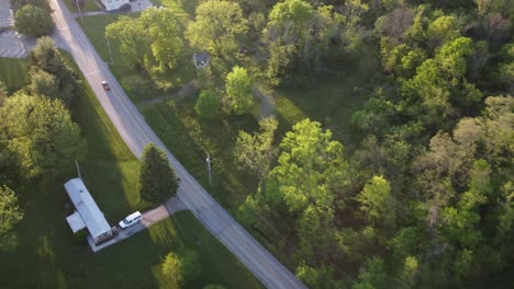 late afternoon birds-eye view over small town road with trees and cars