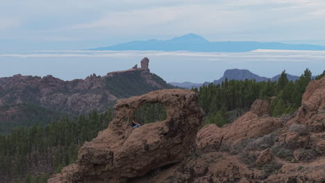Aerial shot of a woman admiring the Roque Nublo and the Teide volcano from the window of the Nublo in Gran Canaria.