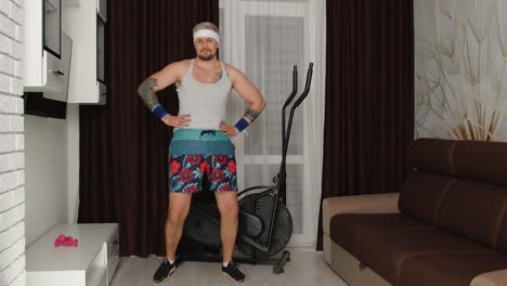 hombre divertido atleta deportista con barba hace ejercicio ejercicios de estiramiento, practicando deporte en casa