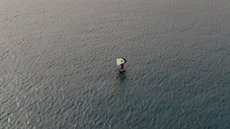 drone shot of man doing windsurfing in the sea