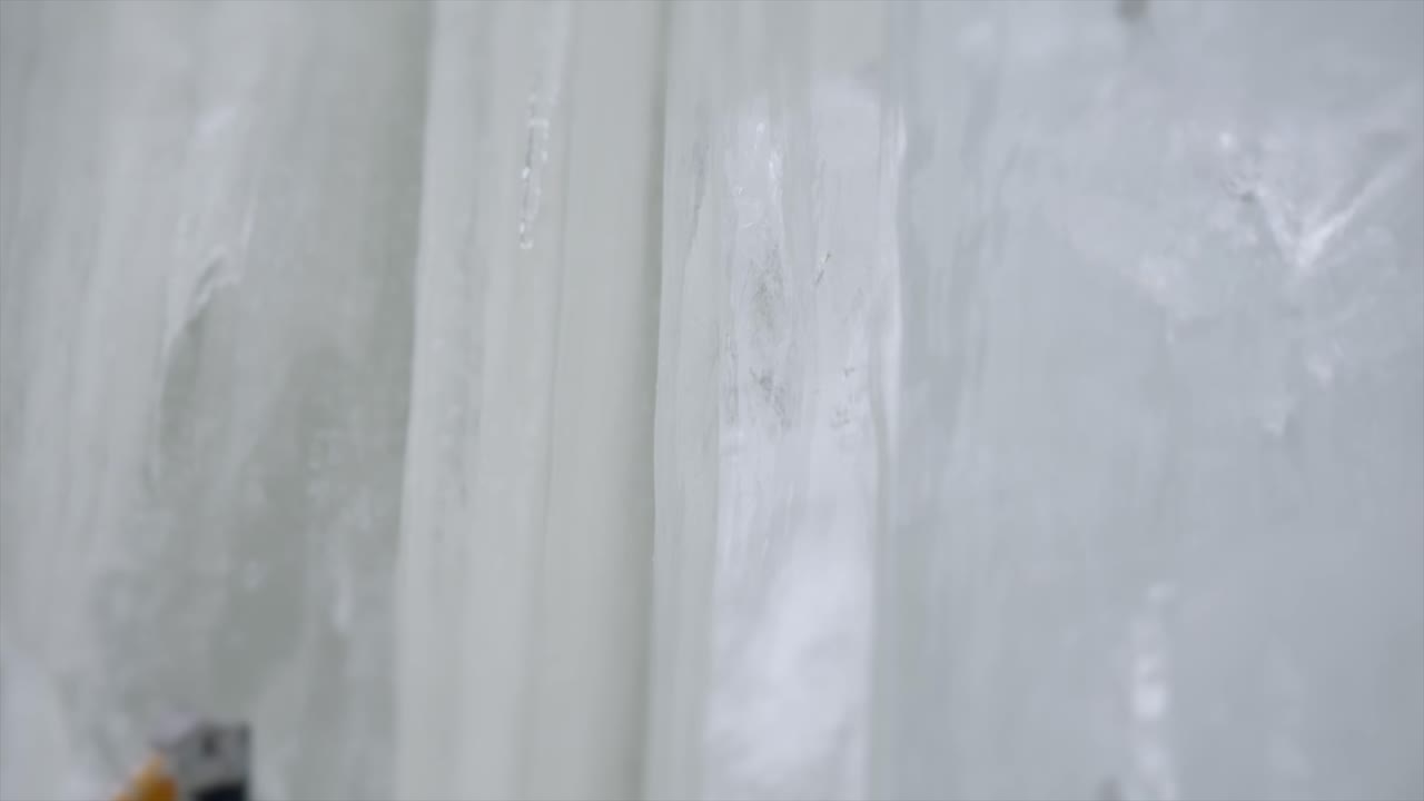 겨울 산악인은 얼어붙은 바위 슬로 모에서 얼음 도끼 등반 기법을 사용합니다.