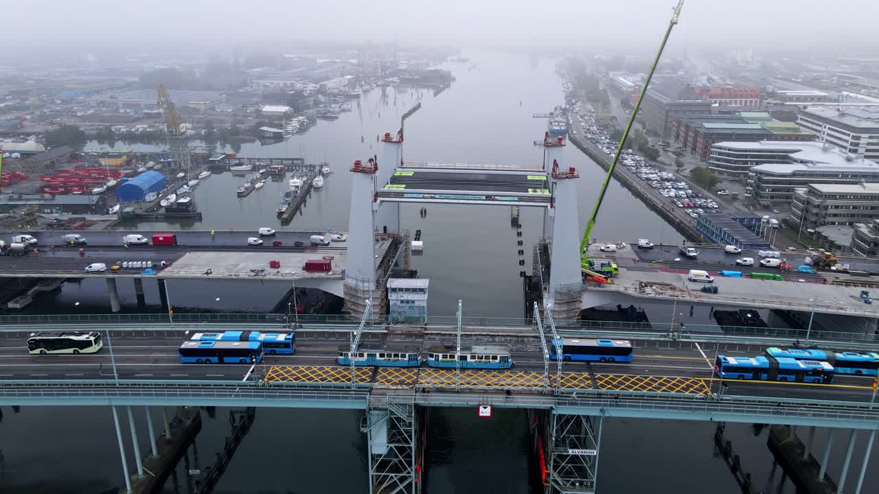 스웨덴 예테보리의 고타 강을 가로지르는 오래된 다리 옆에 건설 중인 새로운 다리의 공중 전망 - 풀백 드론 샷