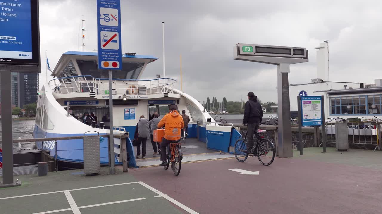 Cyclists and pedestrians boarding the ferry on a rainy day in Amsterdam, The Netherlands