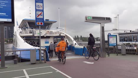 cyclists and pedestrians boarding the ferry on a rainy day in amsterdam, the netherlands