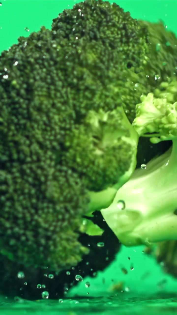 Broccoli freschi e verdi che cadono nell'acqua con schizzi.