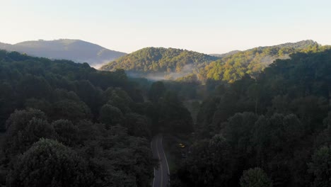 4k drone video flying above trees along mountain road in smoky mountains near asheville, nc on foggy morning