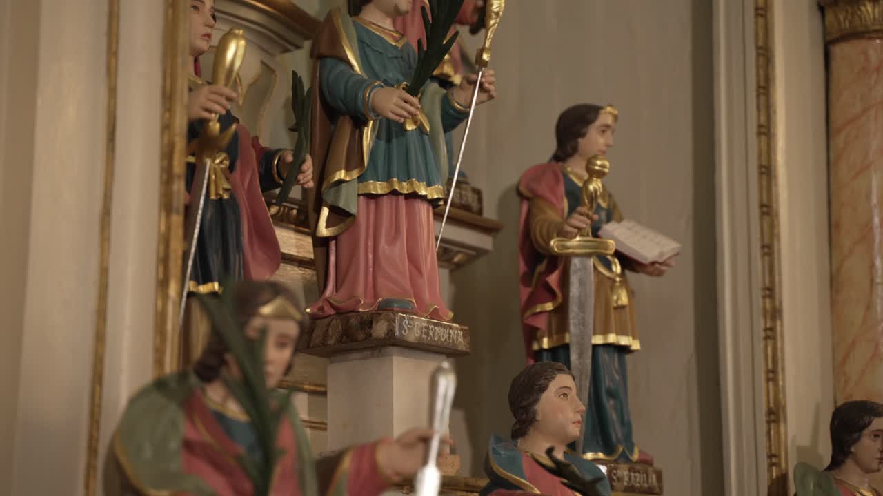 estatuas religiosas ornamentadas de santos que sostienen símbolos en un interior de iglesia ricamente decorado