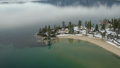 descenso aéreo sobre una playa de arena de invierno en el lago tahoe nevada con nevadas hasta la línea de agua