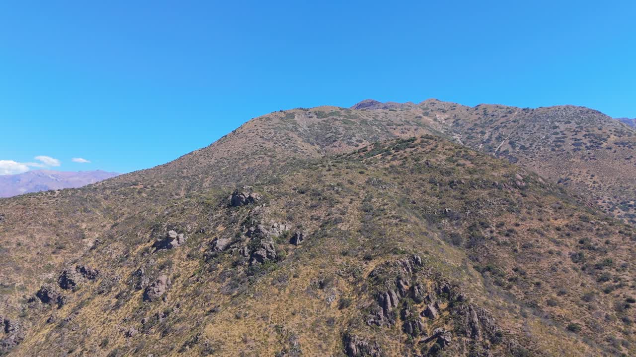 Vista aerea di una catena montuosa arida sotto un cielo azzurro e limpido.