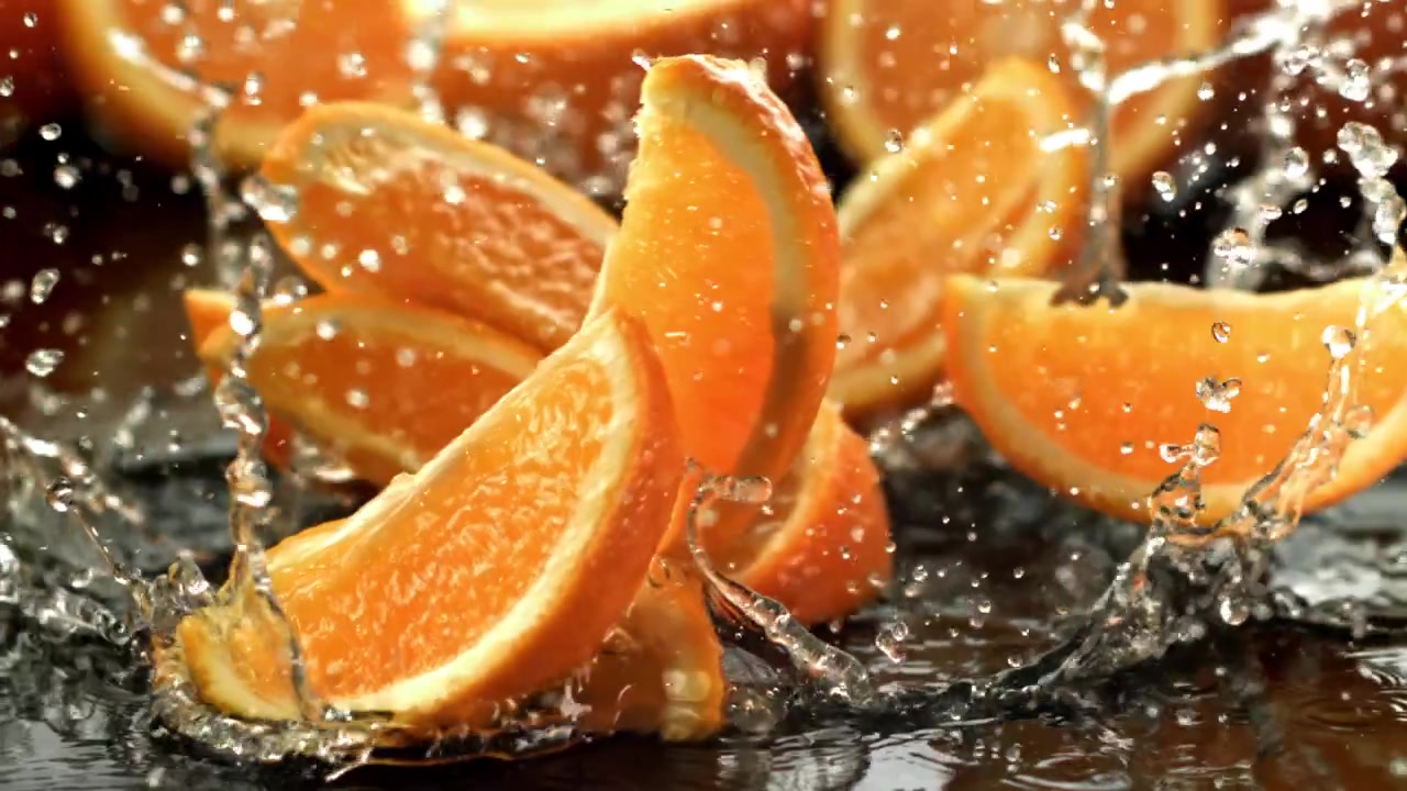 Fette d'arancia che cadono e schizzano nell'acqua al rallentatore.