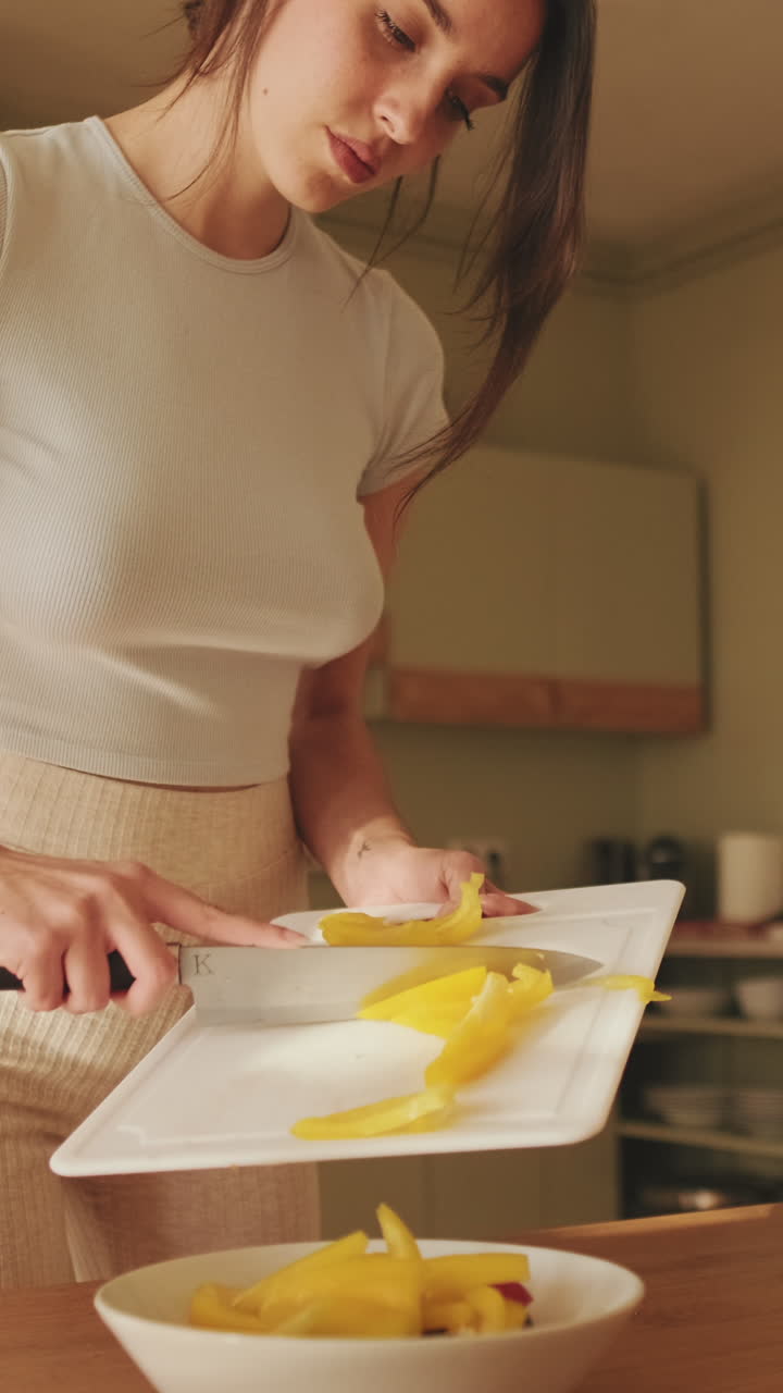 Woman cutting yellow pepper in kitchen