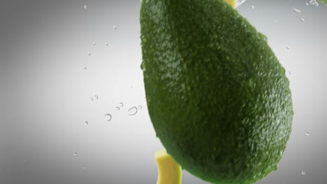 aguacate con rebanadas y salpicaduras cayendo sobre un fondo gris oscuro