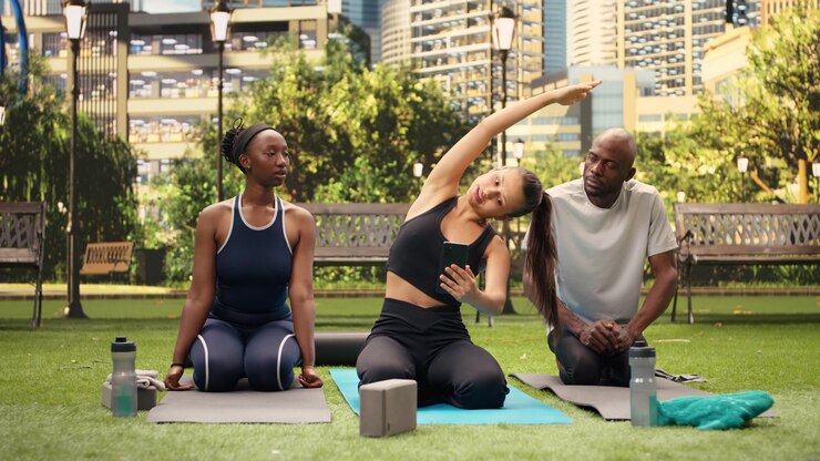 Woman shows content on smartphone to yoga participants as they sit together