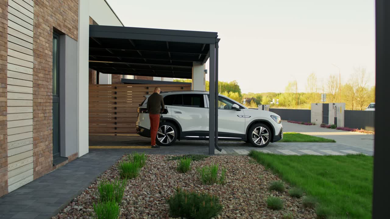 Mann lader en elektrisk SUV hjemme