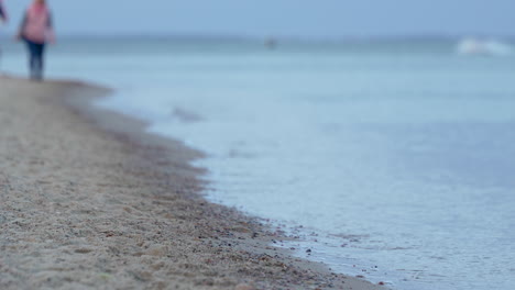 rhythmic waves gently lap shores as romantic couple walks in backdrop