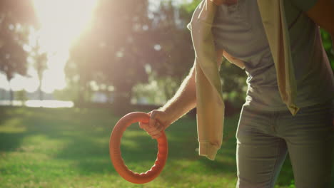 smiling man giving pink puller toy teasing golden retriever in sunlight park