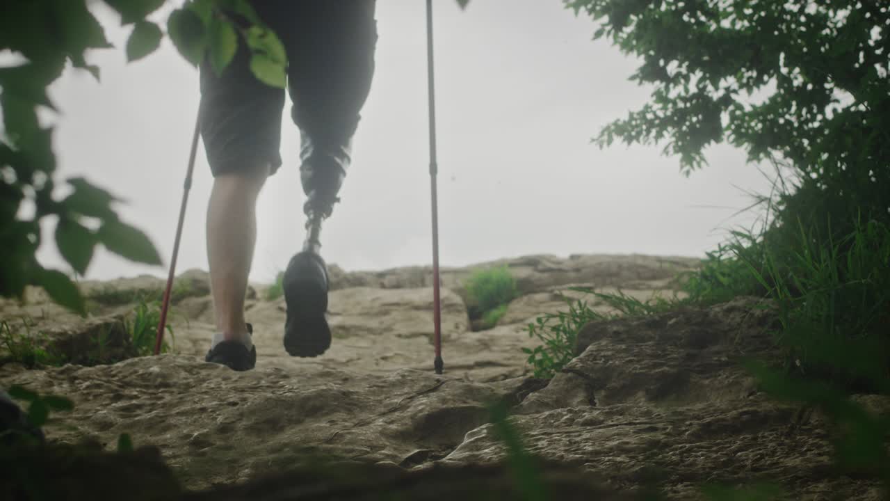 인공 다리를 가진 남성 하이커. 장애인 남자가 바위를 고 산으로 여행하는 시간을 즐기고 있습니다.