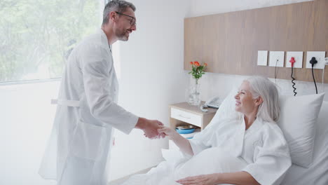 cirujano visitando y estrechando la mano con una paciente adulta en una cama de hospital