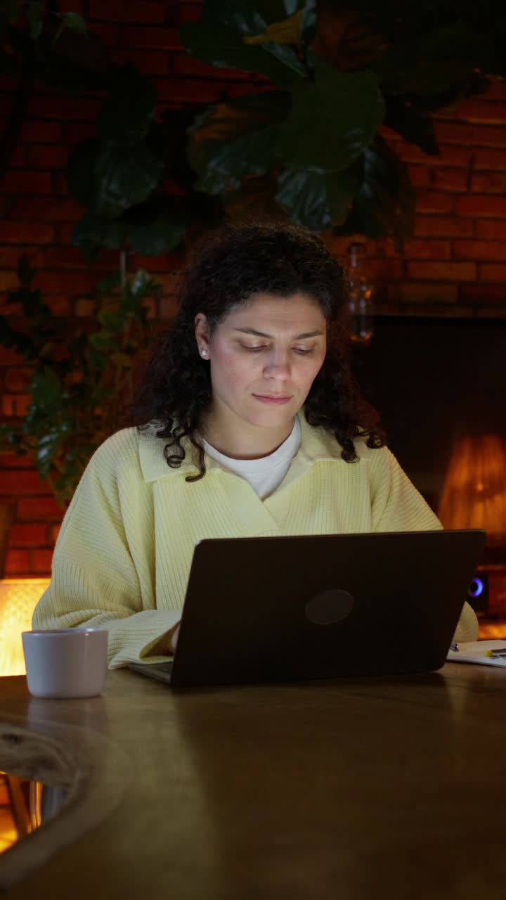 mujer trabajando en una computadora portátil en casa por la noche