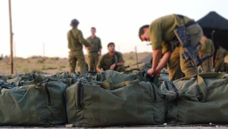 close-up of a military bag with combat gear as soldiers prepare for fighting in the background