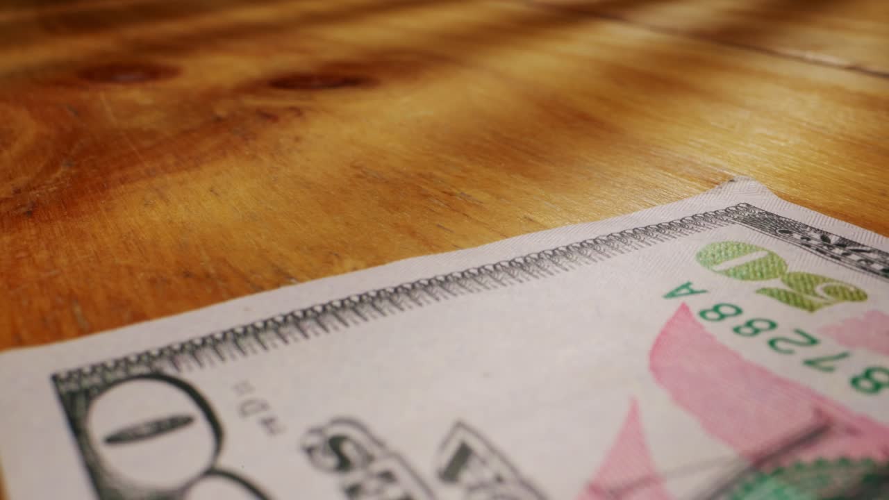 A closeup view of a fifty dollar bill on a polished wooden table, highlighting its intricate design