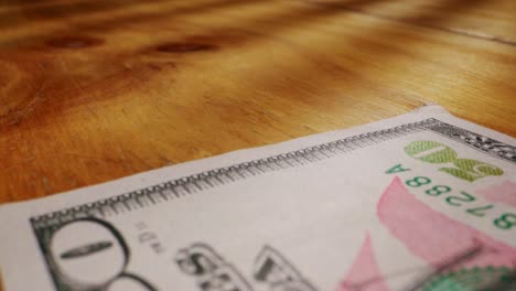 a closeup view of a fifty dollar bill on a polished wooden table, highlighting its intricate design