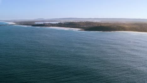 aerial shot capturing vast oceanfront horizon, with clear blue sea stretching toward distant shoreline, highlighting coastal beauty and peaceful nature of the landscape