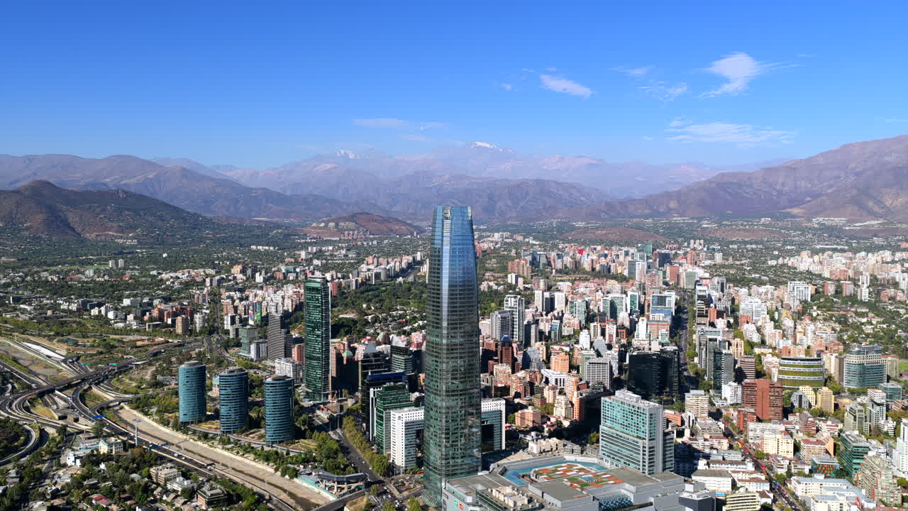 Ampio panorama aereo di Santiago che mostra moderne torri, vasti quartieri urbani e le Ande sotto un cielo limpido e vivace.