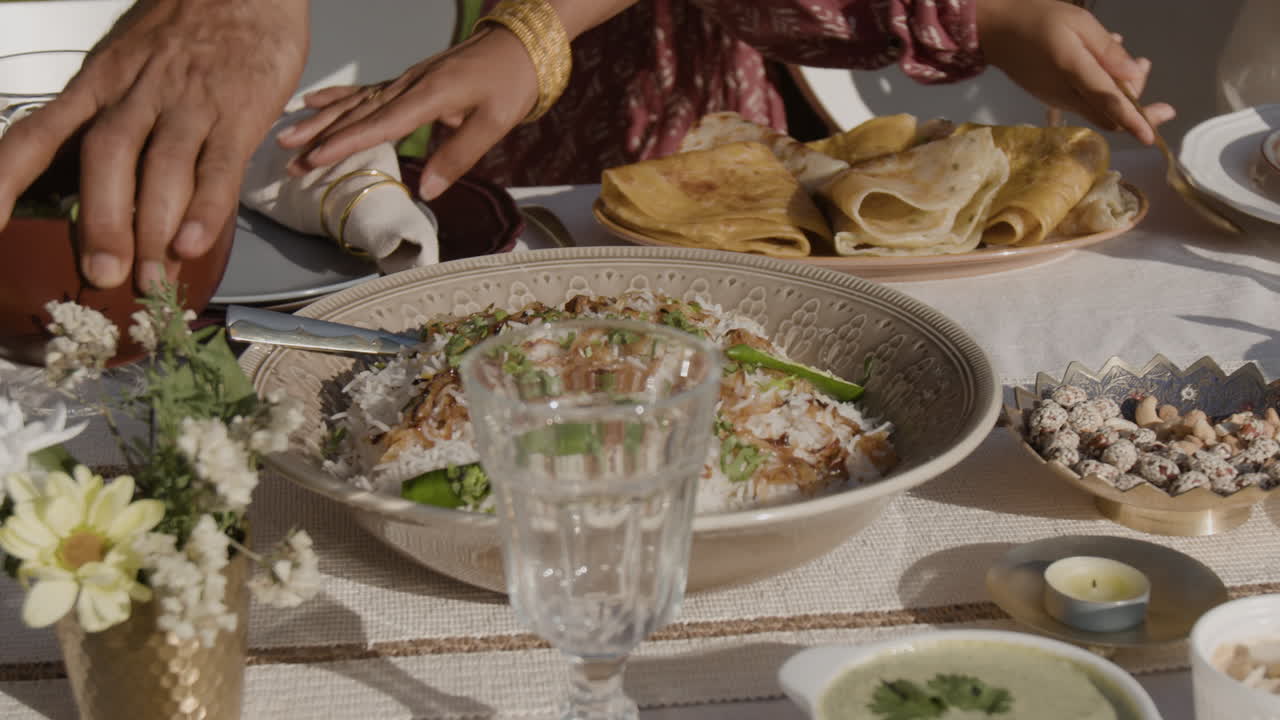 People serving a variety of dishes, including rice and pancakes, at an outdoor dining table