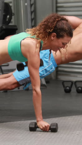 pareja en forma haciendo filas de pesas en el gimnasio de crossfit
