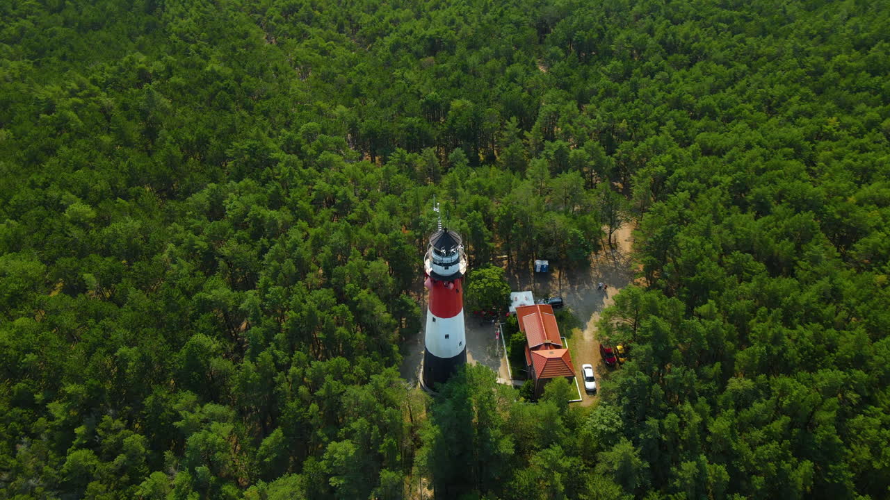 dron girando alrededor del faro de stilo y el faro del bosque verde ubicado en osetnik en la costa polaca del mar báltico, cerca de la aldea de sasino, aérea