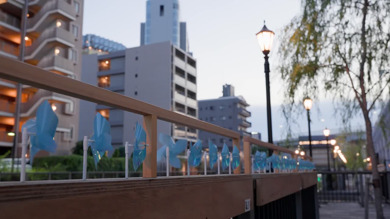 A shot capturing blue pinwheels decorating the railing of the promenade at Tokyo Mizumachi along the Kita-jūkken-gawa River