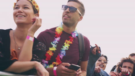 group of young friends waiting behind barrier at entrance to music festival site