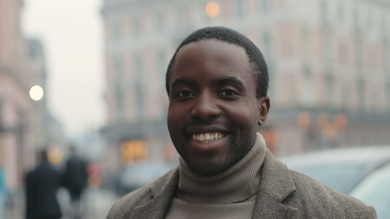 Portrait of happy african american businessman with a beard smiling to the camera cheerfully in the street in autumn
