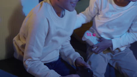 dos niños jóvenes en casa divirtiéndose jugando con la consola de juegos de computadora en la tv sosteniendo controladores tarde en la noche