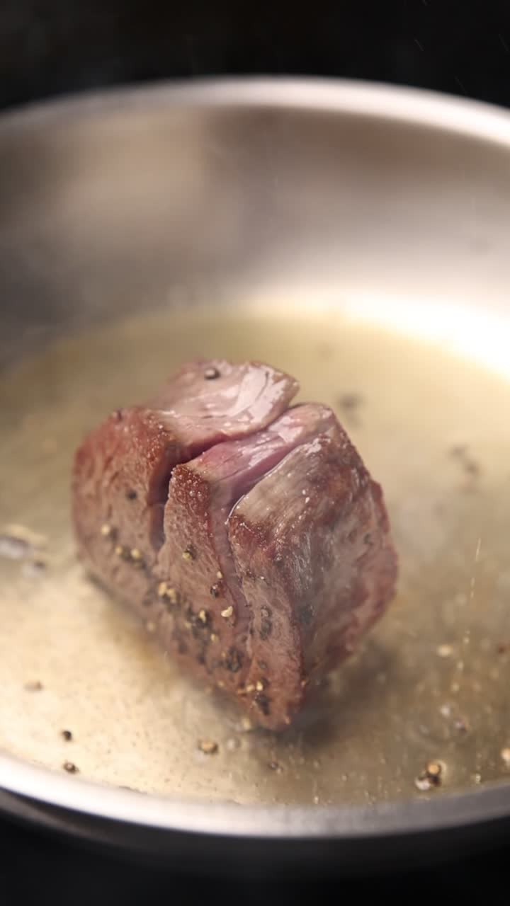 Primo piano di una bistecca che sfrigola in una padella calda