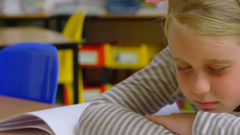 Vista-Frontal-De-Una-Colegiala-Caucásica-Durmiendo-En-El-Escritorio-En-El-Aula-De-La-Escuela-4k