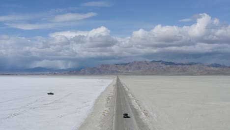 car traveling fast on road trip in desert salt flats road, aerial view