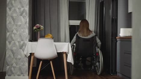 woman moves closer to window spinning wheels of wheelchair