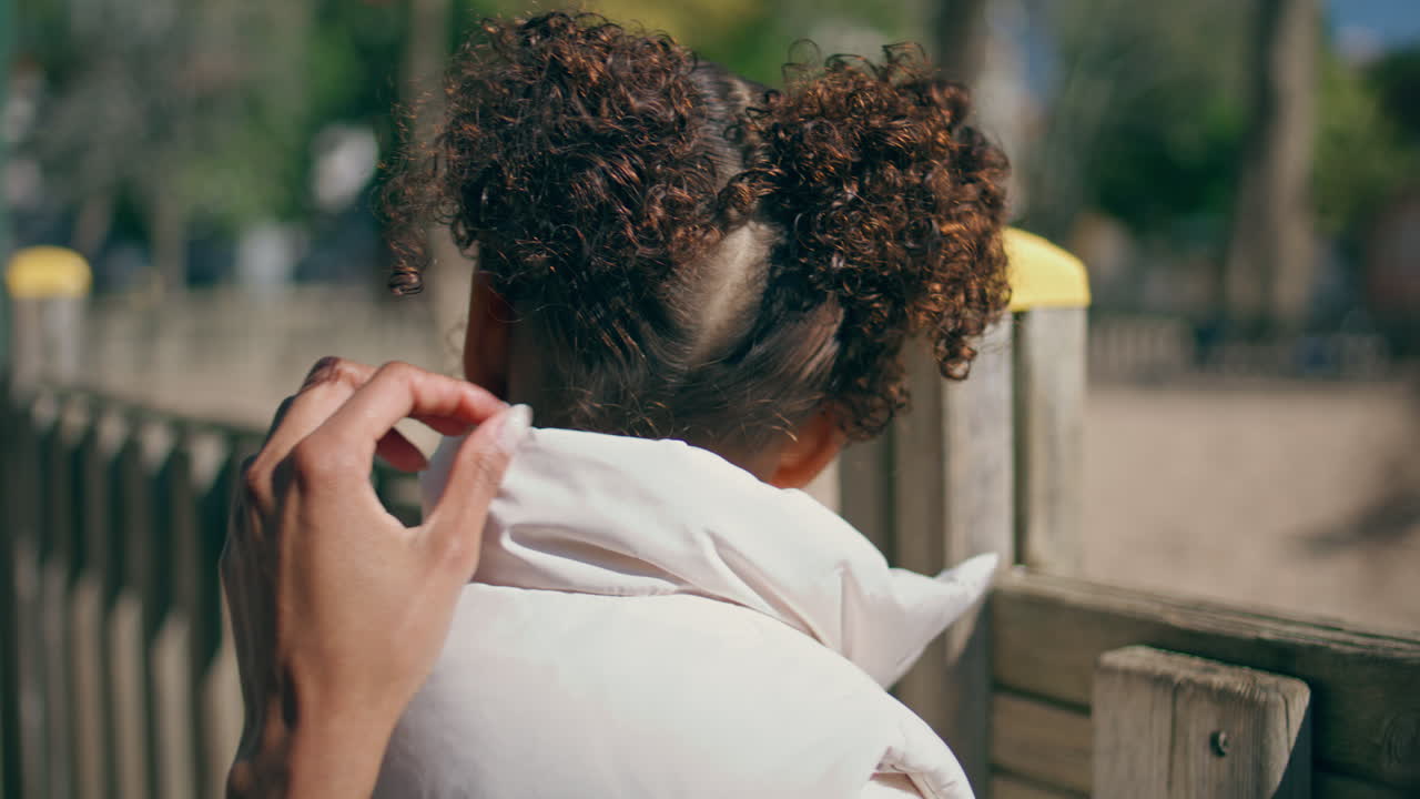 niño de pie en la valla del parque en primer plano. niña disfrutando del fin de semana en familia
