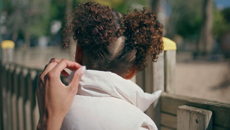 child standing at park fence closeup. girl enjoy family weekend