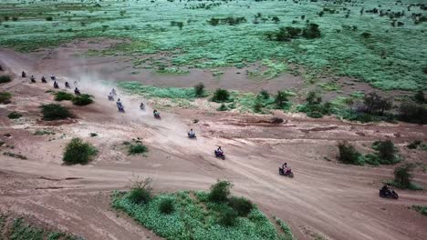 huge group of motorcycle riders driving across the wilderness of kenya in east africa